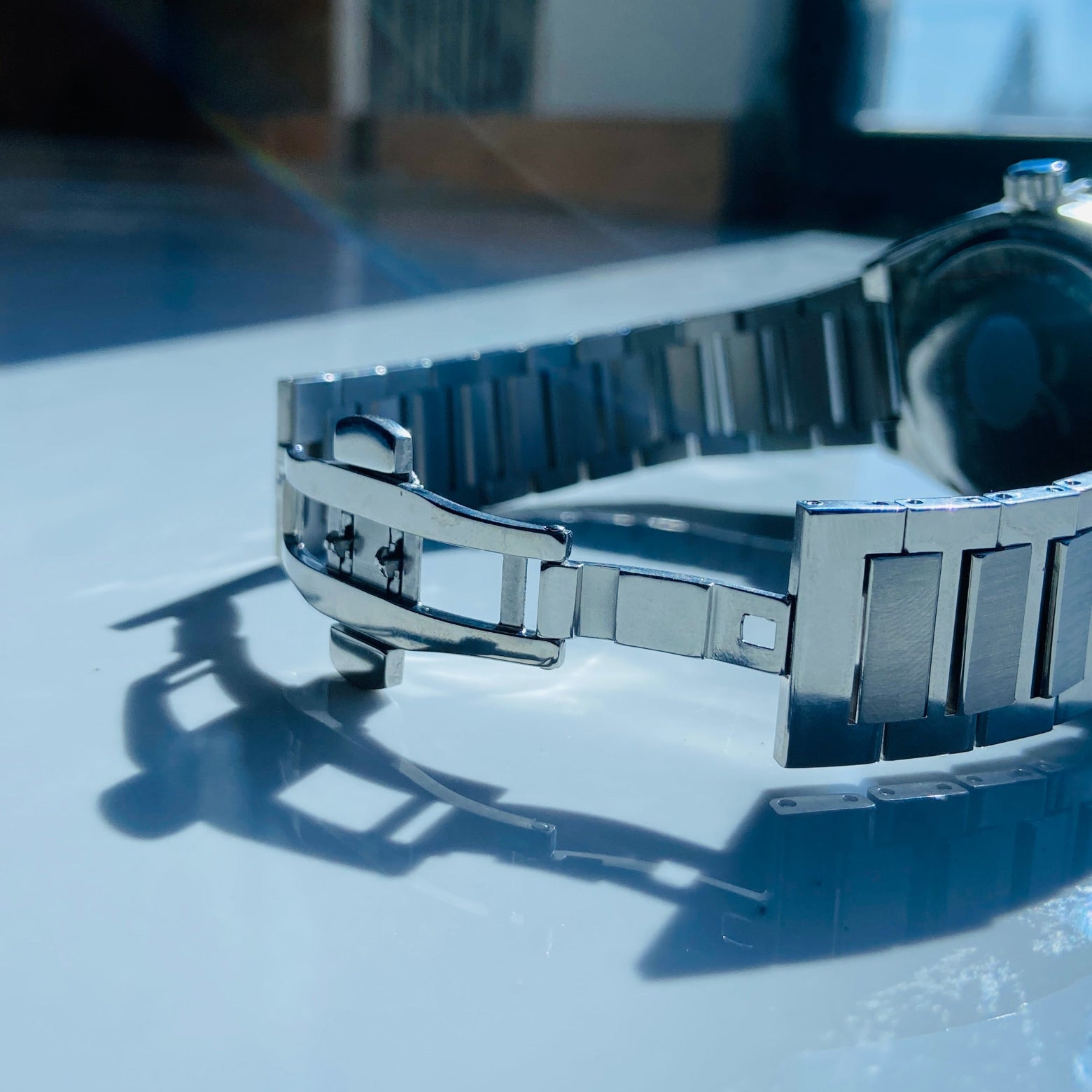 Silver watch band on a reflective surface with a blurred background