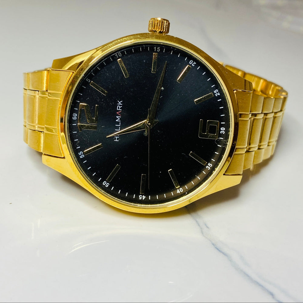 Gold wristwatch with a black face on a light surface Gold wristwatch with black dial on a white cushion against a light background Gold Hallmark Watch watches mens kings DSJ Deep Shine Jewellers timeless timepiece time exclusive jewellery jewelry Your Time To Shine