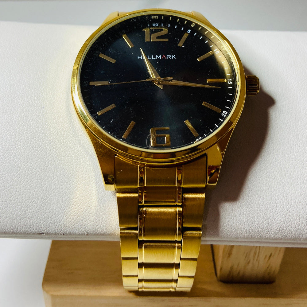 Gold wristwatch with black dial on a white cushion, placed on a wooden stand. Gold wristwatch with black dial on a white cushion against a light background Gold Hallmark Watch watches mens kings DSJ Deep Shine Jewellers timeless timepiece time exclusive jewellery jewelry Your Time To Shine