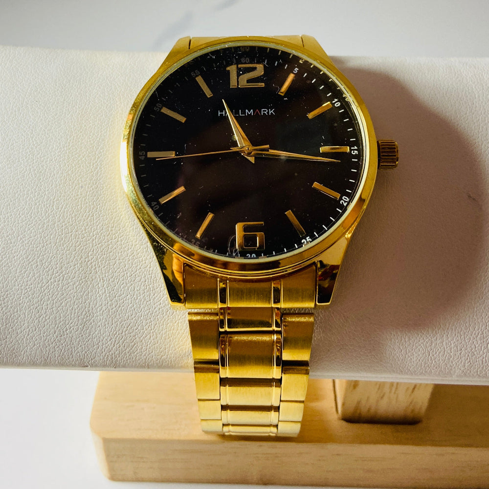 Gold wristwatch with black dial on a white surface Gold wristwatch with black dial on a white cushion against a light background Gold Hallmark Watch watches mens kings DSJ Deep Shine Jewellers timeless timepiece time exclusive jewellery jewelry Your Time To Shine