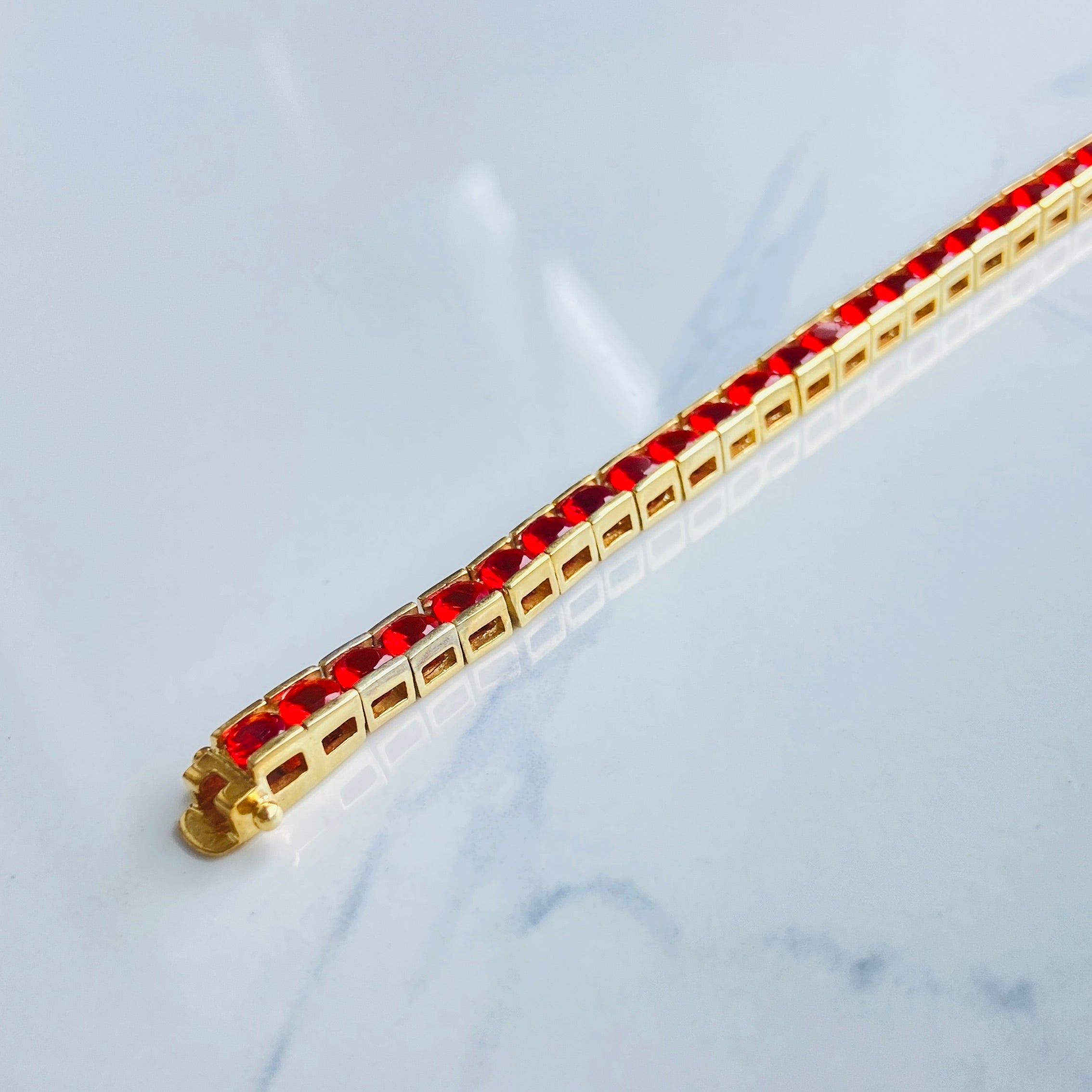 Gold bracelet with red gemstones on a white cushion Gold red ruby bracelet women queens ladies female tennis bracelet ruby red 925 silver sterling silver gold plated golden exclusive affordable luxury jewellery jewelry Deep Shine Jewellers DSJ Your Time To Shine trending best seller buy purchase bracelets 