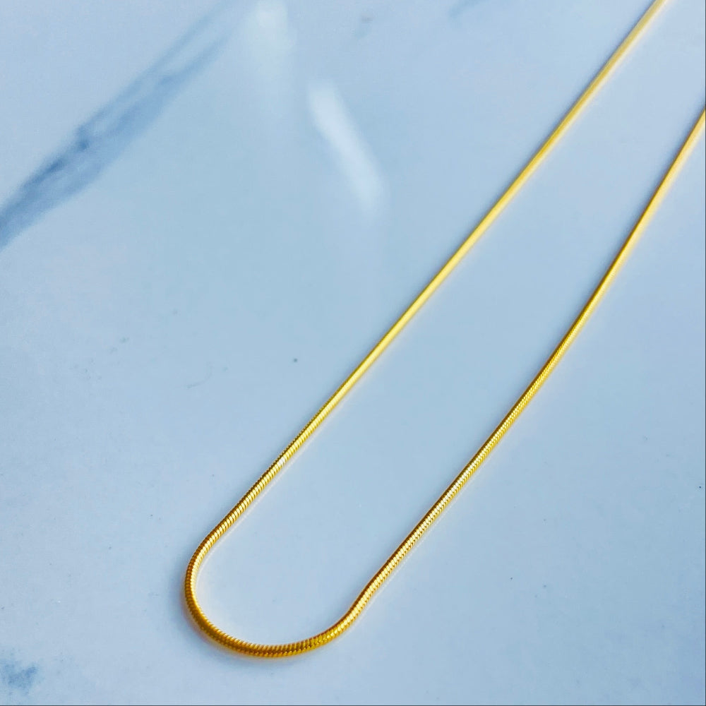 Gold bar on a light blue marble surface gold snake bone chain women men ladies gents kinds queens exclusive craftsmanship affordable luxury high quality premium jewellery jewelry Deep Shine Jewellers gold plated golden 925 silver sterling silver Your Time To Shine DSJ