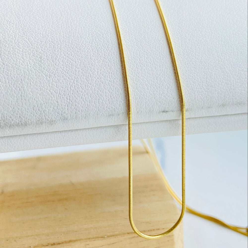 Gold necklace on a white surface with a wooden block Gold bar on a light blue marble surface gold snake bone chain women men ladies gents kinds queens exclusive craftsmanship affordable luxury high quality premium jewellery jewelry Deep Shine Jewellers gold plated golden 925 silver sterling silver Your Time To Shine DSJ