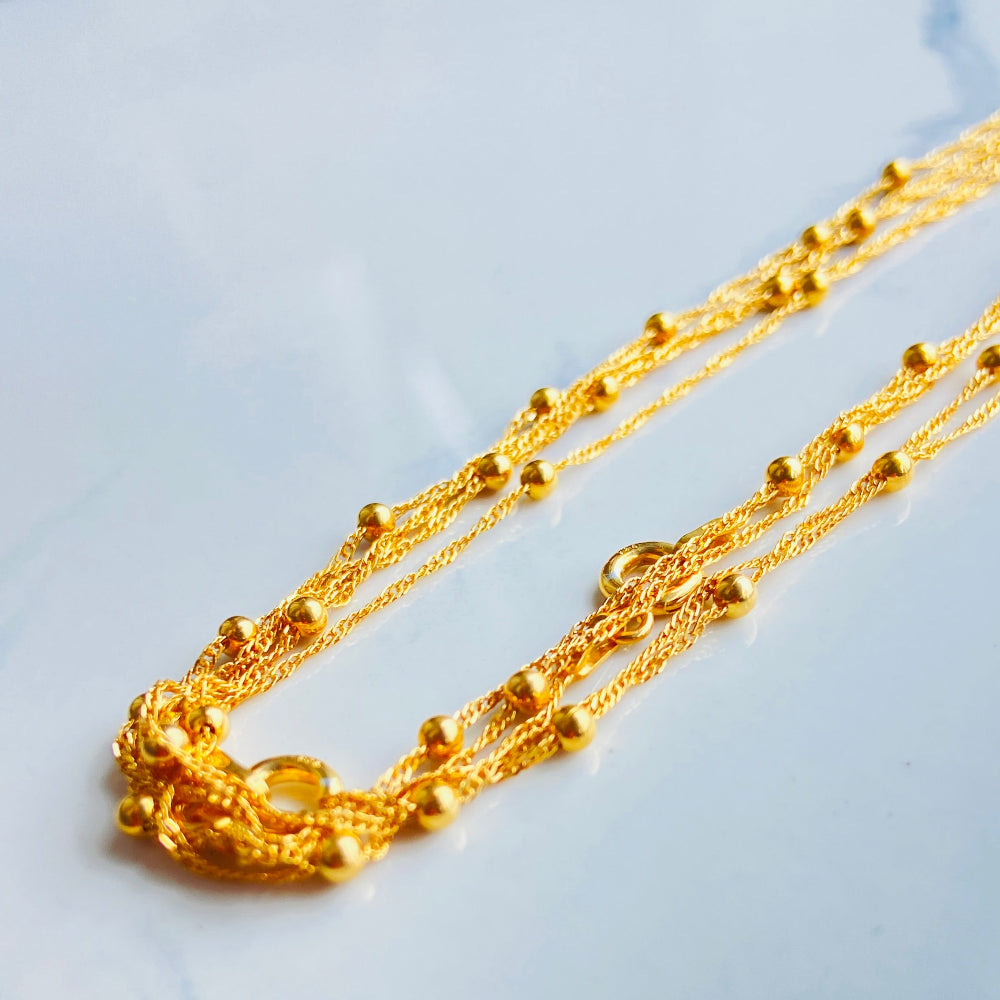 Gold chain necklace on a light blue marble surface gold balled singapore chain women ladies queens exclusive affordable luxury 925 silver sterling silver gold plated golden beauty beads craftsmanship by Deep Shine Jewellers jewellery jewelry DSJ Your Time To Shine trending best sellers store best in cape town