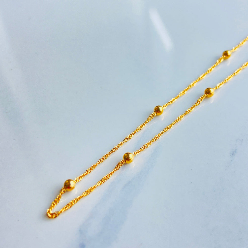 Gold chain necklace on a light blue marble surface gold balled singapore chain women ladies queens exclusive affordable luxury 925 silver sterling silver gold plated golden beauty beads craftsmanship by Deep Shine Jewellers jewellery jewelry DSJ Your Time To Shine trending best sellers store best in cape town