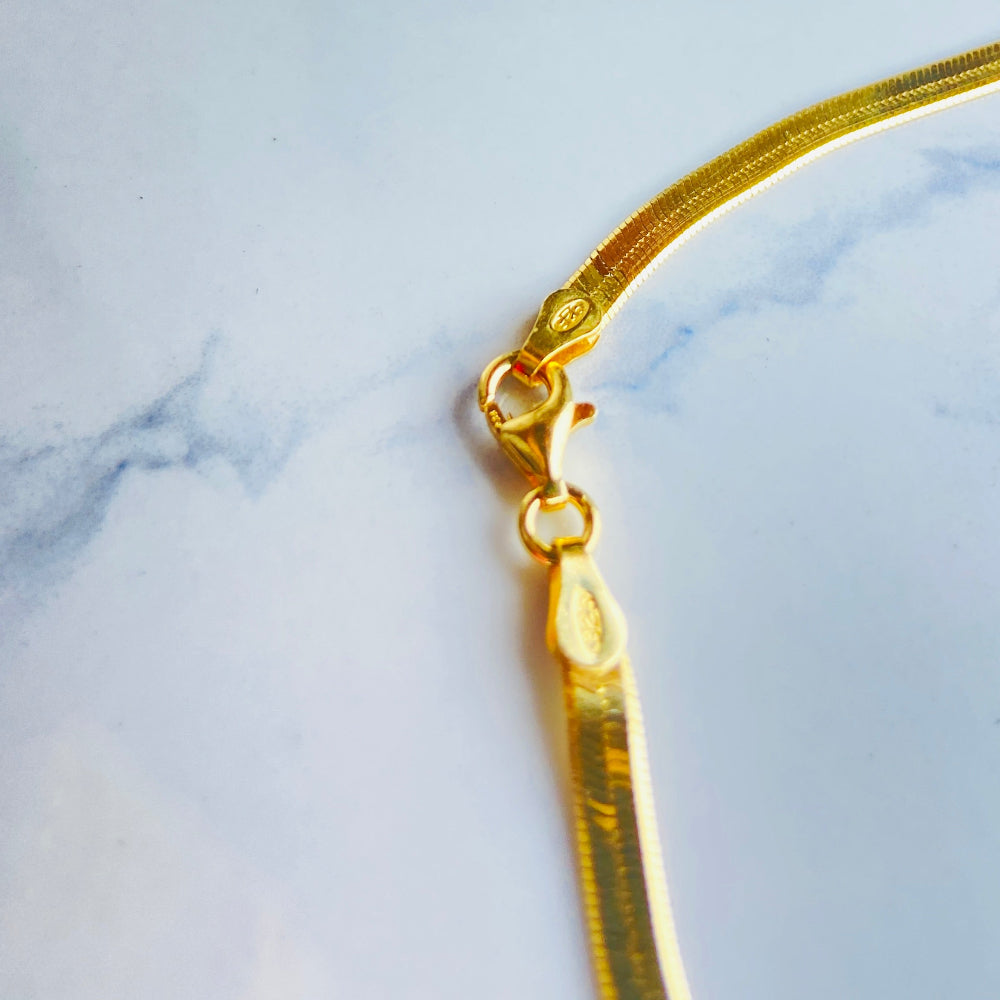 Gold hair clip on a marble background gold herringbone chain necklace women ladies queens 925 silver sterling silver premium jewellery jewelry affordable luxury exclusive craftsmanship Deep Shine Jewellers DSJ Your Time To Shine best seller trending shop now store million