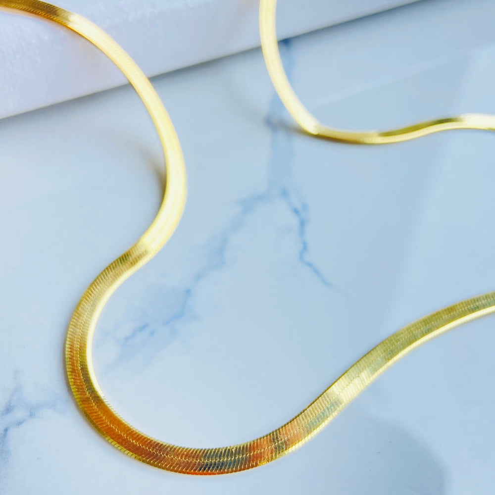 Gold necklace on a light blue marble surface Gold hair clip on a marble background gold herringbone chain necklace women ladies queens 925 silver sterling silver premium jewellery jewelry affordable luxury exclusive craftsmanship Deep Shine Jewellers DSJ Your Time To Shine best seller trending shop now store million