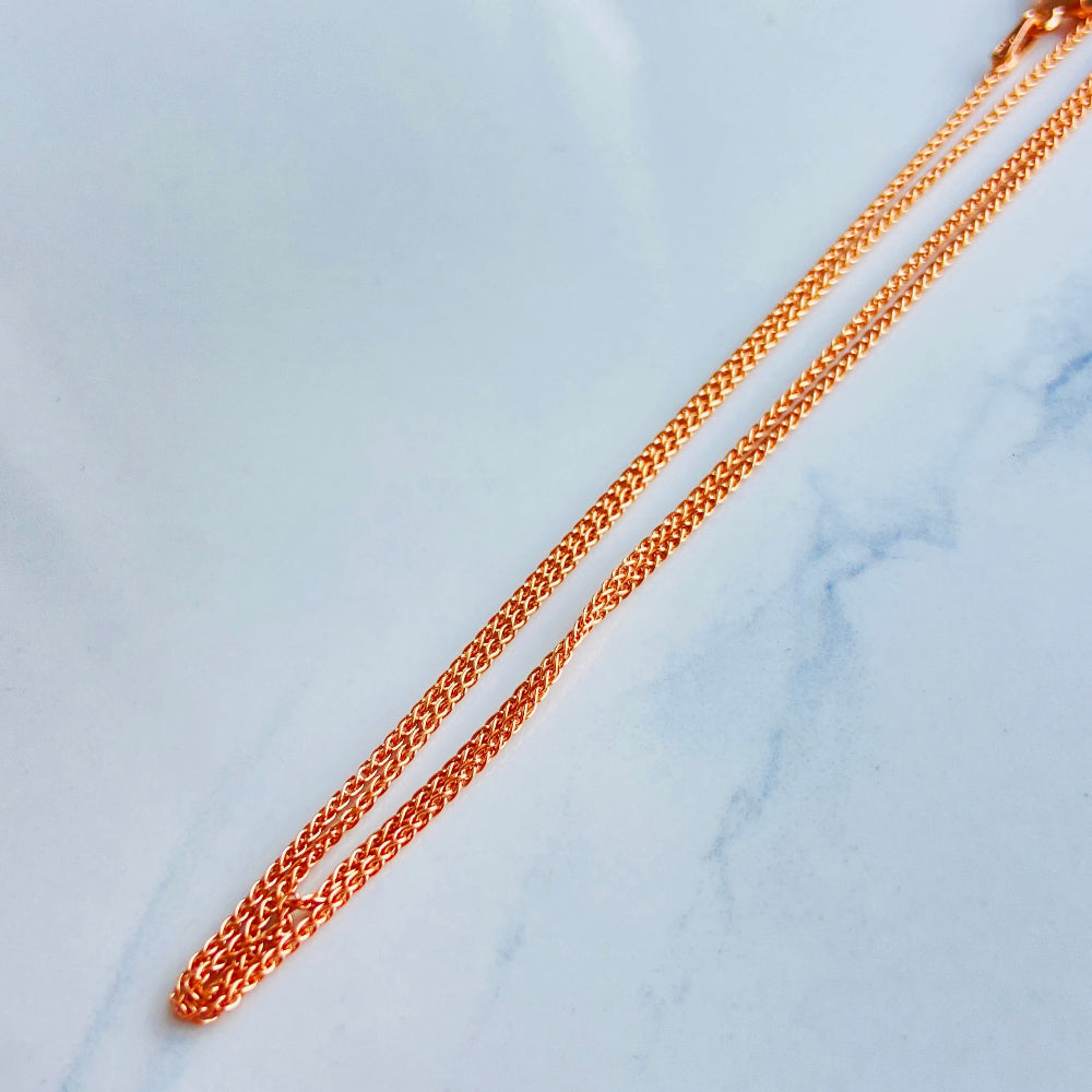 Gold chain on a light blue marble surface Rose gold necklace on a light blue marble surface rose gold wheat chain necklace women ladies queens 925 silver sterling silver rose gold plating roses premium jewellery jewelry affordable luxury elegant best seller trending Deep Shine Jewellers DSJ Your Time To Shine