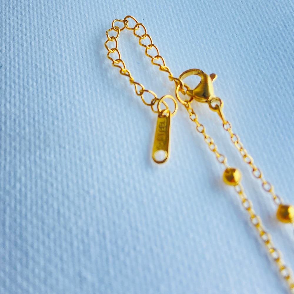 Gold chain earring on a light blue textured background old bow-shaped pendant on a chain against a light blue background gold bow balled chain necklace gold plated golden women ladies queens stainless steel premium jewellery jewelry affordable luxury Deep Shine Jewellery Your Time To Shine best sellers trending for him her