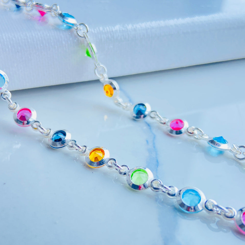 Multicolored beaded bracelet on a marble surface Colorful cross-shaped pendant on a dark surface Colourful Silver Cross Jewel Chain Exclusively by Deep Shine Jewellers. colourful gemstones diamonds lab diamonds sapphire pink yellow orange purple 925 silver sterling silver exclusive craftsmanship affordable luxury premium quality jewellery jewelry trending best sellers Your Time To Shine DSJ 