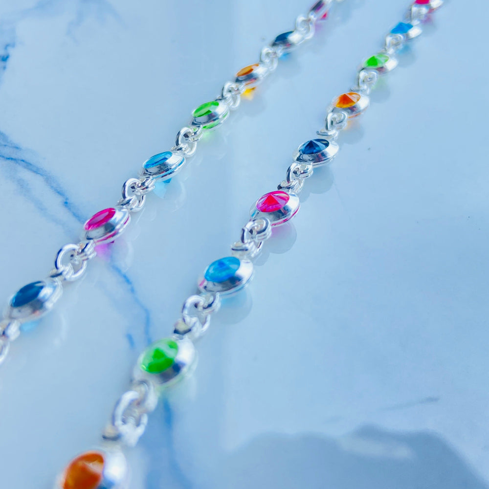 Colorful beaded necklace on a light blue background Colorful cross-shaped pendant on a dark surface Colourful Silver Cross Jewel Chain Exclusively by Deep Shine Jewellers. colourful gemstones diamonds lab diamonds sapphire pink yellow orange purple 925 silver sterling silver exclusive craftsmanship affordable luxury premium quality jewellery jewelry trending best sellers Your Time To Shine DSJ 