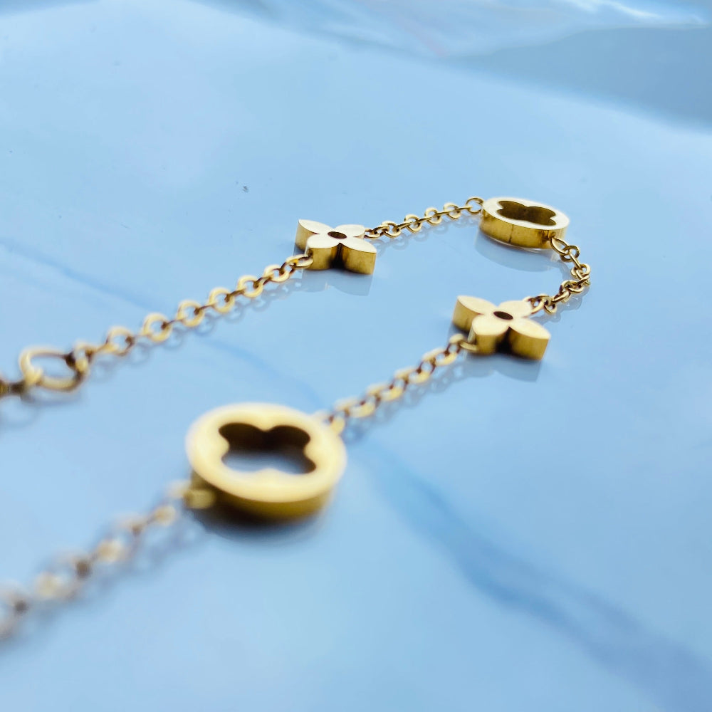 Gold bracelet with clover-shaped charms on a light blue background gold clover bracelet womens mens ladies gents queens kings van cleef and arpels charm gold plated golden premium jewellery jewelry exclusive craftsmanship cape town best sellers stainless steel trending modern classy Deep Shine Jewellers DSJ Your Time To Shine online store affordable luxury 