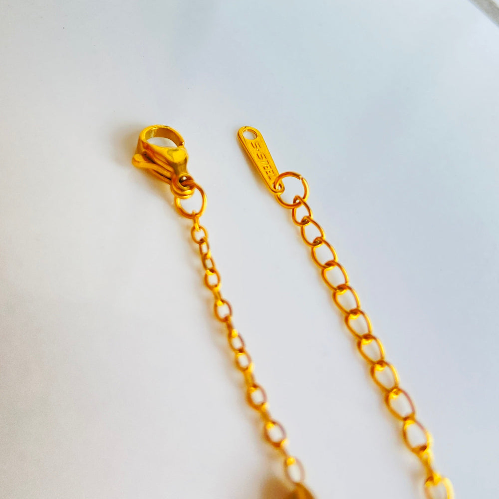 Gold chain with clasp on a white marble surface Gold bracelet with clover-shaped charms on a light blue background gold clover bracelet womens mens ladies gents queens kings van cleef and arpels charm gold plated golden premium jewellery jewelry exclusive craftsmanship cape town best sellers stainless steel trending modern classy Deep Shine Jewellers DSJ Your Time To Shine online store affordable luxury 