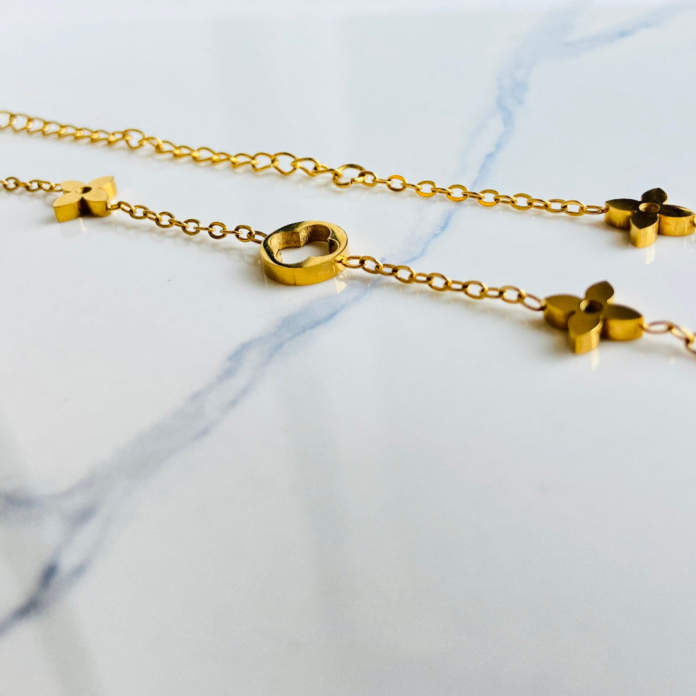 Gold necklace with star-shaped pendants on a marble surface Gold bracelet with clover-shaped charms on a light blue background gold clover bracelet womens mens ladies gents queens kings van cleef and arpels charm gold plated golden premium jewellery jewelry exclusive craftsmanship cape town best sellers stainless steel trending modern classy Deep Shine Jewellers DSJ Your Time To Shine online store affordable luxury 