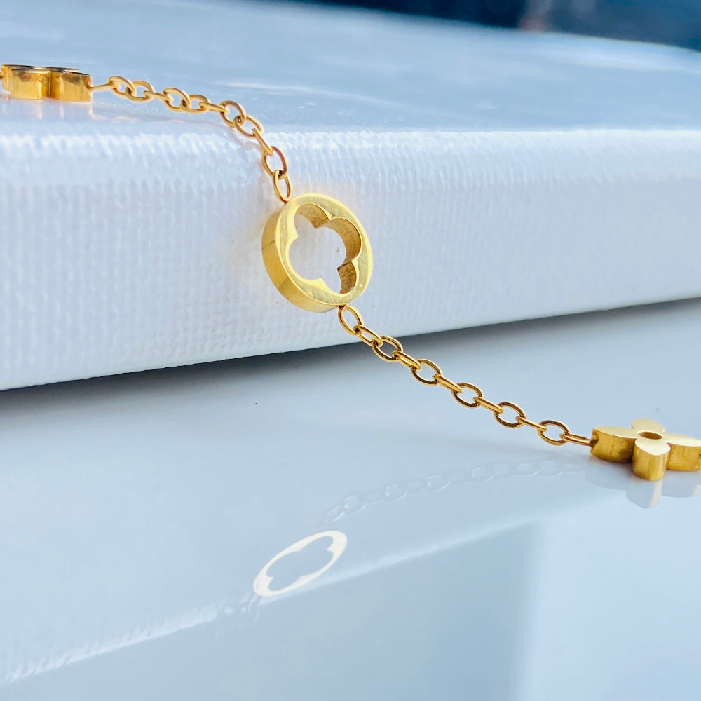Gold bracelet on a white surface with a blurred background Gold bracelet with clover-shaped charms on a light blue background gold clover bracelet womens mens ladies gents queens kings van cleef and arpels charm gold plated golden premium jewellery jewelry exclusive craftsmanship cape town best sellers stainless steel trending modern classy Deep Shine Jewellers DSJ Your Time To Shine online store affordable luxury 