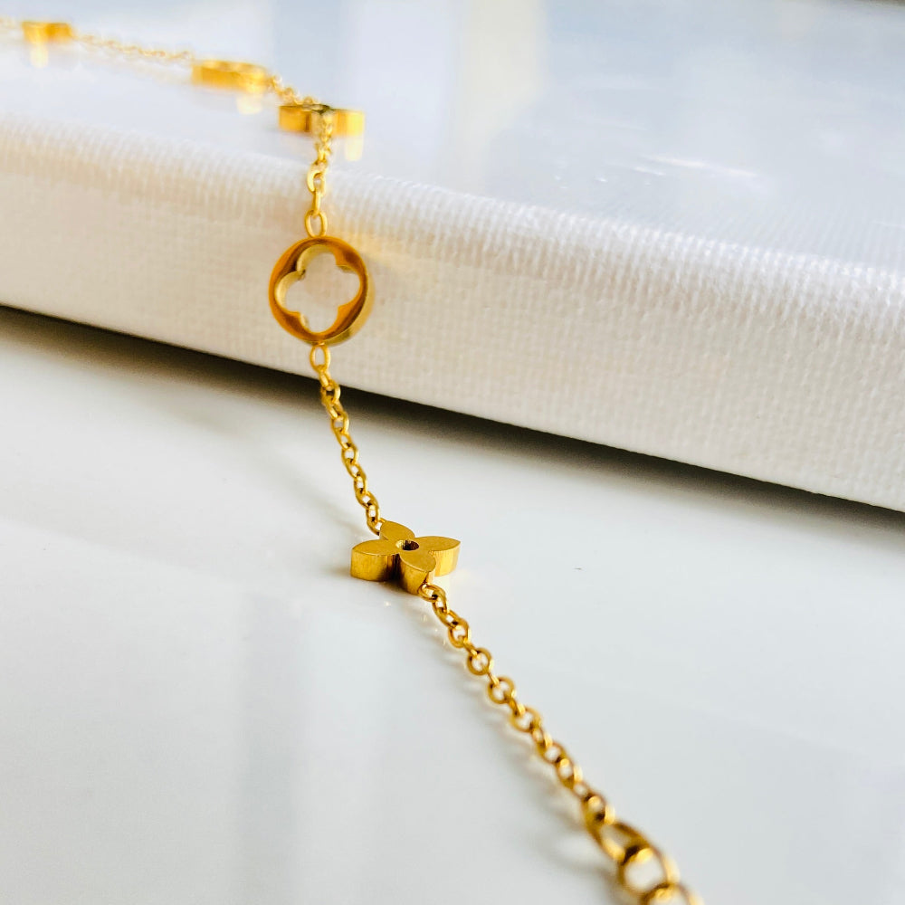Gold bracelet with heart-shaped clasp on a white surface Gold bracelet with clover-shaped charms on a light blue background gold clover bracelet womens mens ladies gents queens kings van cleef and arpels charm gold plated golden premium jewellery jewelry exclusive craftsmanship cape town best sellers stainless steel trending modern classy Deep Shine Jewellers DSJ Your Time To Shine online store affordable luxury 