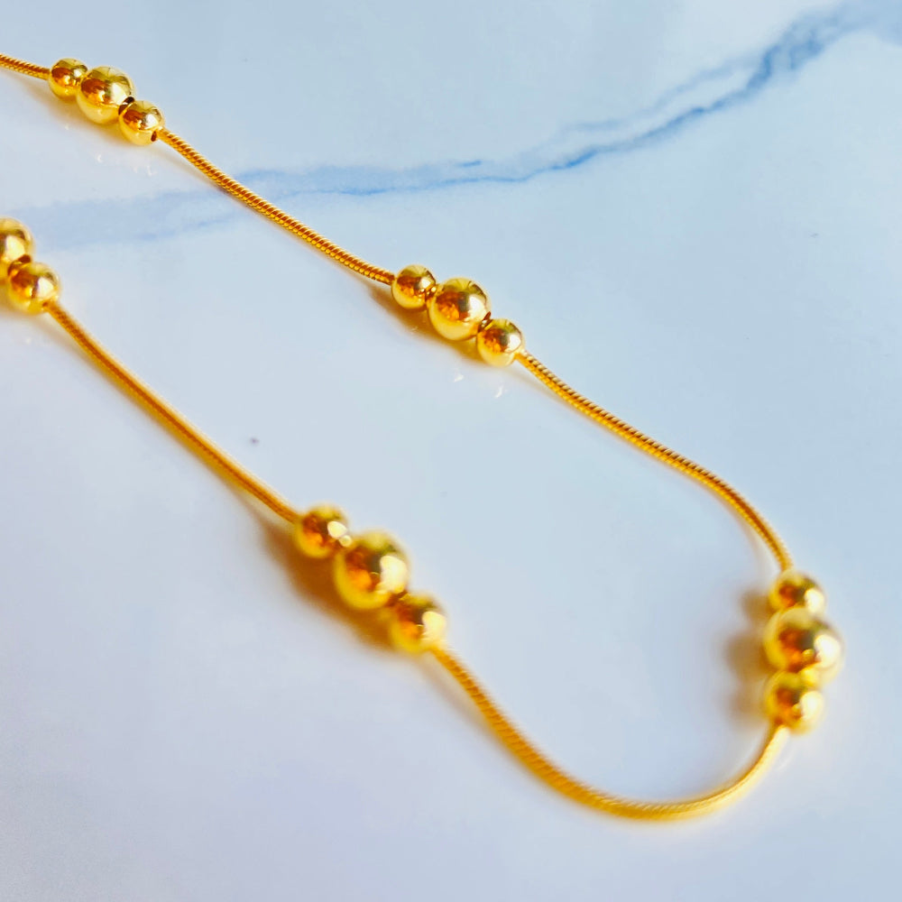 Gold necklace with beads on a light blue fabric background Gold beaded necklace on a light blue background gold ball and snake bracelet women ladies queens gold plated golden 925 silver sterling silver exclusive craftsmanship affordable luxury premium quality jewellery jewelry Deep Shine Jewellery DSJ Your Time To Shine best sellers trending chrismas sale gifts 