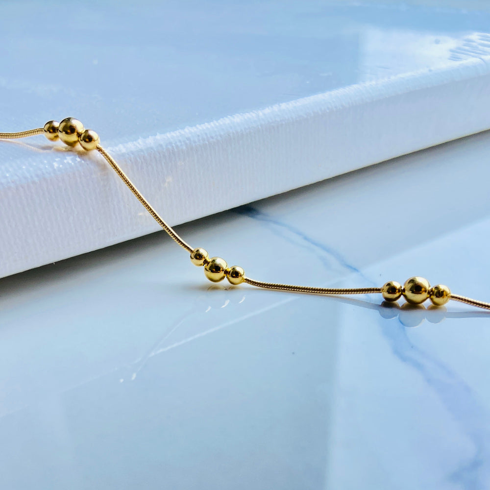 Gold bracelet with beads on a light blue surface Gold beaded necklace on a light blue background gold ball and snake bracelet women ladies queens gold plated golden 925 silver sterling silver exclusive craftsmanship affordable luxury premium quality jewellery jewelry Deep Shine Jewellery DSJ Your Time To Shine best sellers trending chrismas sale gifts 