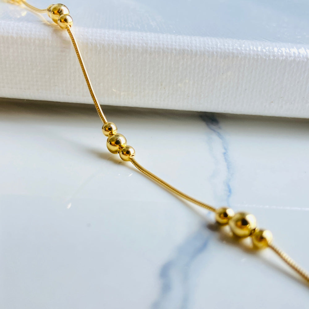 Gold beaded necklace on a marble surface Gold beaded necklace on a light blue background gold ball and snake bracelet women ladies queens gold plated golden 925 silver sterling silver exclusive craftsmanship affordable luxury premium quality jewellery jewelry Deep Shine Jewellery DSJ Your Time To Shine best sellers trending chrismas sale gifts 
