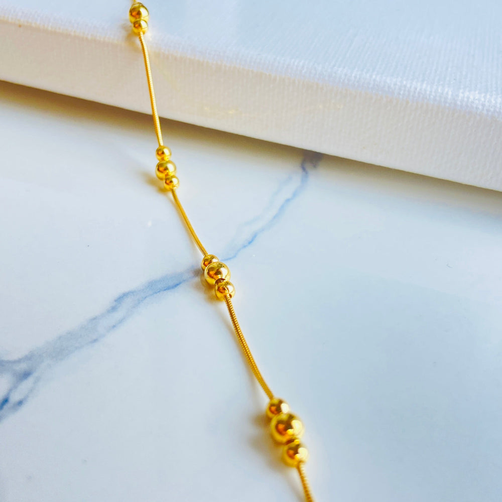 Gold necklace on a marble surface with a light blue background Gold beaded necklace on a light blue background gold ball and snake bracelet women ladies queens gold plated golden 925 silver sterling silver exclusive craftsmanship affordable luxury premium quality jewellery jewelry Deep Shine Jewellery DSJ Your Time To Shine best sellers trending chrismas sale gifts 