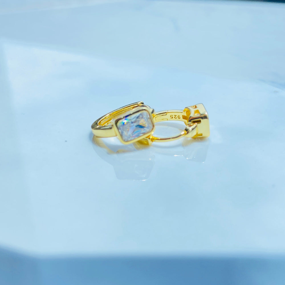 Gold ring with a clear gemstone on a white surface Gold hoop earring with clear stones on a reflective surface with blue sky background gold single stone sleeper earrings women ladies queens gold plated golden cubic zirconia diamond baguette 925 silver sterling silver exclusive craftsmanship high quality premium affordable luxury Deep Shine Jewellers jewellery jewelry Your Time To Shine DSJ