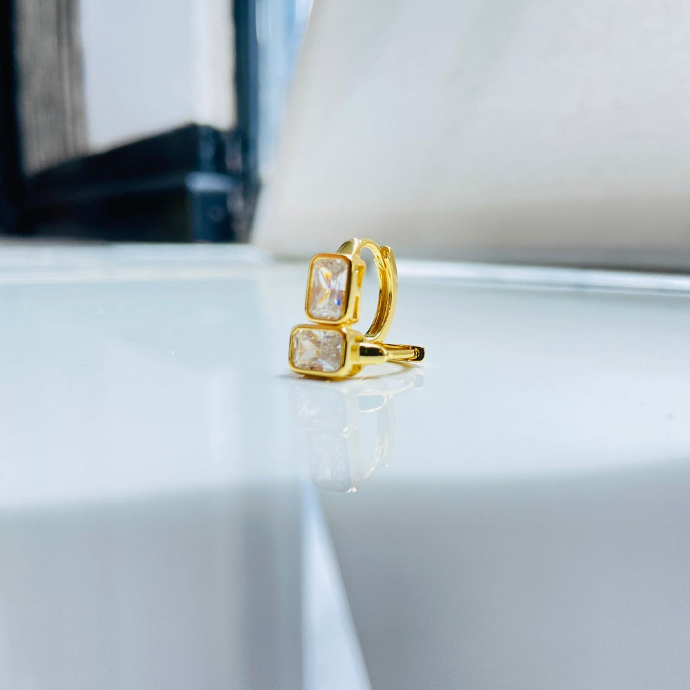 Gold ring with a clear gemstone on a white surface Gold hoop earring with clear stones on a reflective surface with blue sky background gold single stone sleeper earrings women ladies queens gold plated golden cubic zirconia diamond baguette 925 silver sterling silver exclusive craftsmanship high quality premium affordable luxury Deep Shine Jewellers jewellery jewelry Your Time To Shine DSJ