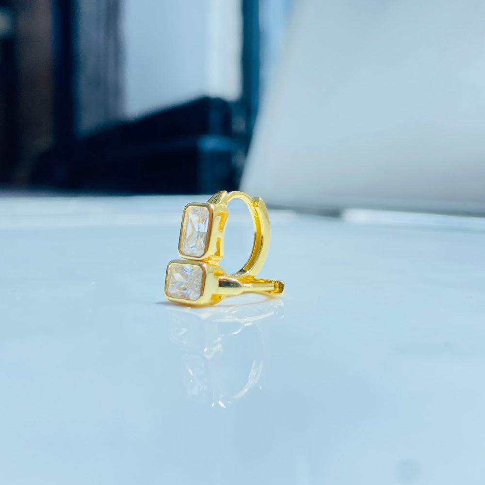 Gold ring with a square stone on a white surface Gold hoop earring with clear stones on a reflective surface with blue sky background gold single stone sleeper earrings women ladies queens gold plated golden cubic zirconia diamond baguette 925 silver sterling silver exclusive craftsmanship high quality premium affordable luxury Deep Shine Jewellers jewellery jewelry Your Time To Shine DSJ