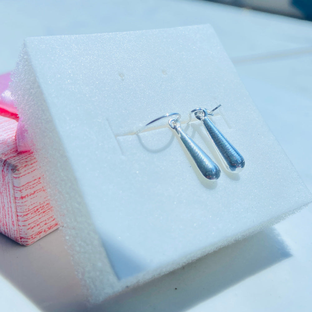 Silver earrings on a white card with a blurred background Pair of earrings on a white card with a blurred background silver teardrop earrings women ladies queens 925 silver sterling silver exclusive craftsmanship Deep Shine Jewellers jewellery jewelry dangle drop trending best seller shine bright Your Time To Shine DSJ