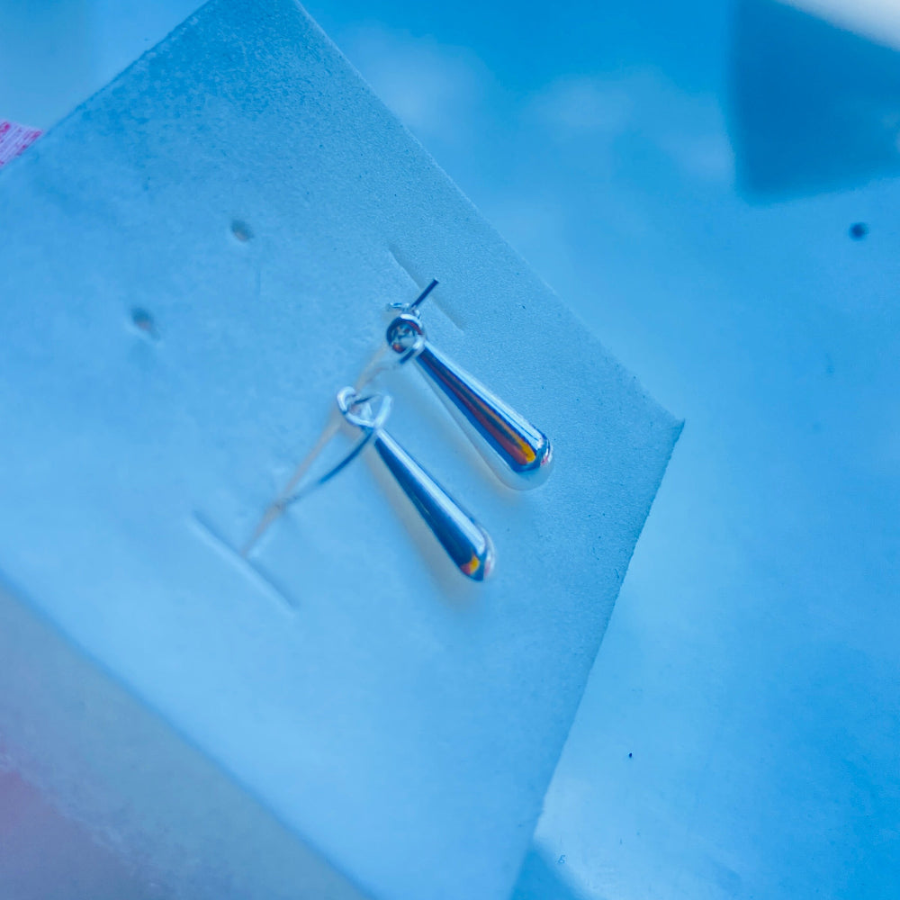 Silver earrings on a clear square card with a blue background Pair of earrings on a white card with a blurred background silver teardrop earrings women ladies queens 925 silver sterling silver exclusive craftsmanship Deep Shine Jewellers jewellery jewelry dangle drop trending best seller shine bright Your Time To Shine DSJ