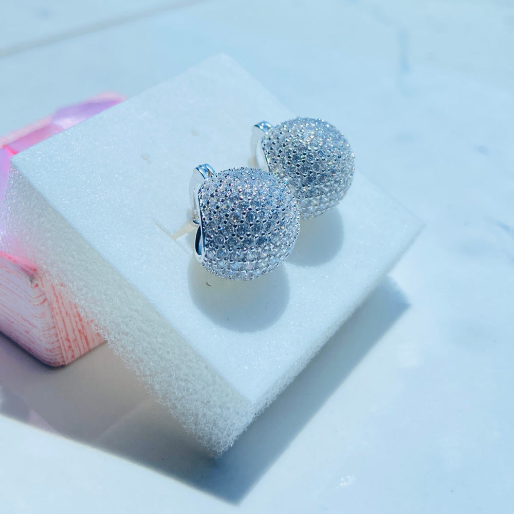 Silver earrings on a white stand with a blurred outdoor background silver ice dome earrings women ladies queens 925 silver sterling silver cubic zirconia diamonds lab diamonds affordable luxury exclusive craftsmanship Deep Shine Jewellers jewellery jewelry DSJ Your Time To Shine limited premium jewellery trending