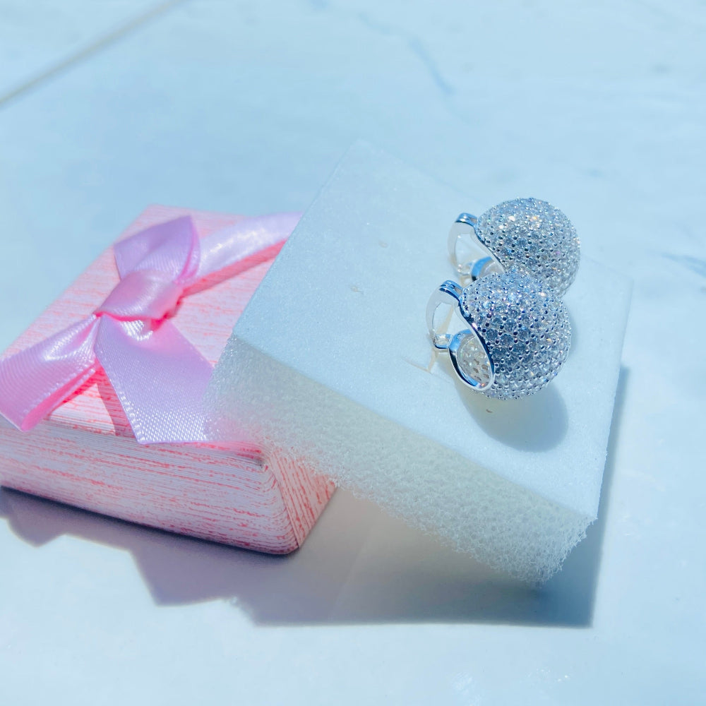 Silver earrings on a white stand with a blurred outdoor background silver ice dome earrings women ladies queens 925 silver sterling silver cubic zirconia diamonds lab diamonds affordable luxury exclusive craftsmanship Deep Shine Jewellers jewellery jewelry DSJ Your Time To Shine limited premium jewellery trending