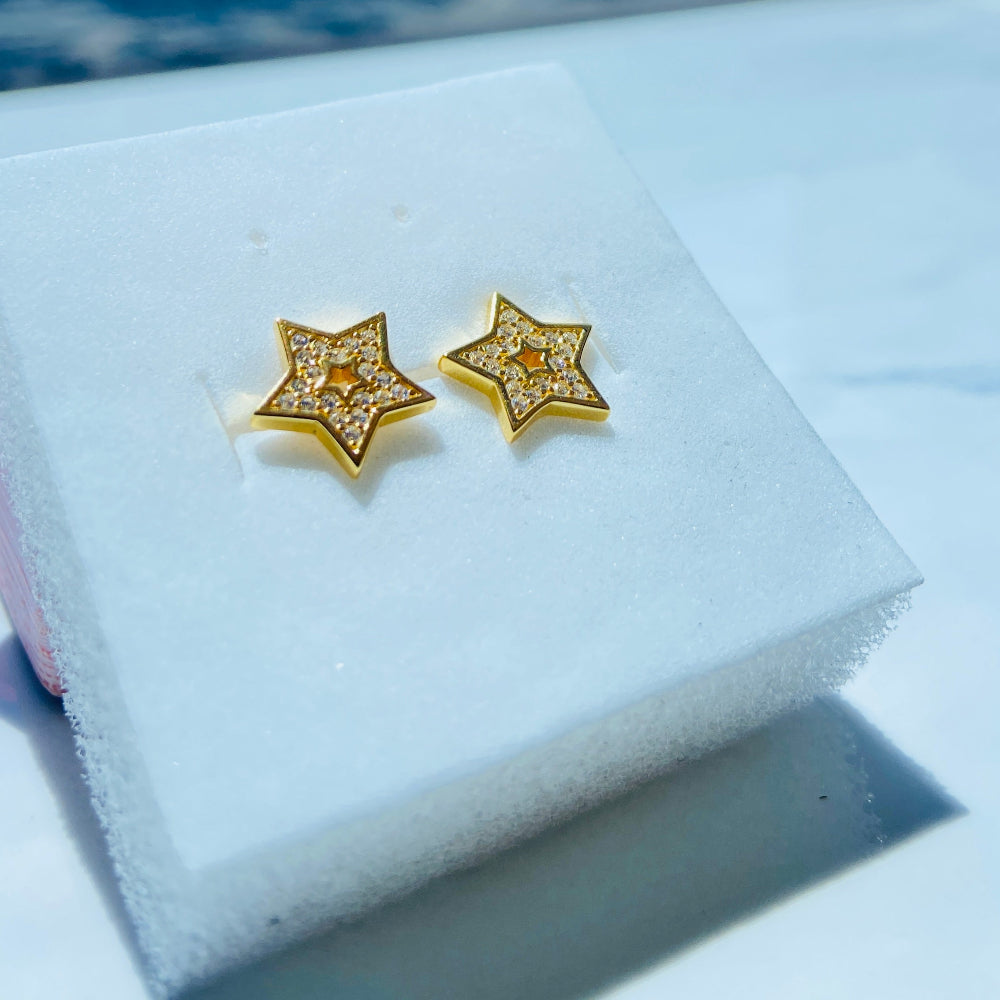 Gold star-shaped earrings on a white cushion with a blue sky background Gold star-shaped earrings on a white box with a scenic background gold iced star stud earring women men ladies gents kings queens 925 silver sterling silver gold plated golden shine exclusive craftsmanship Deep Shine Jewellers Jewellery jewelry trending shop now store bright beauty 