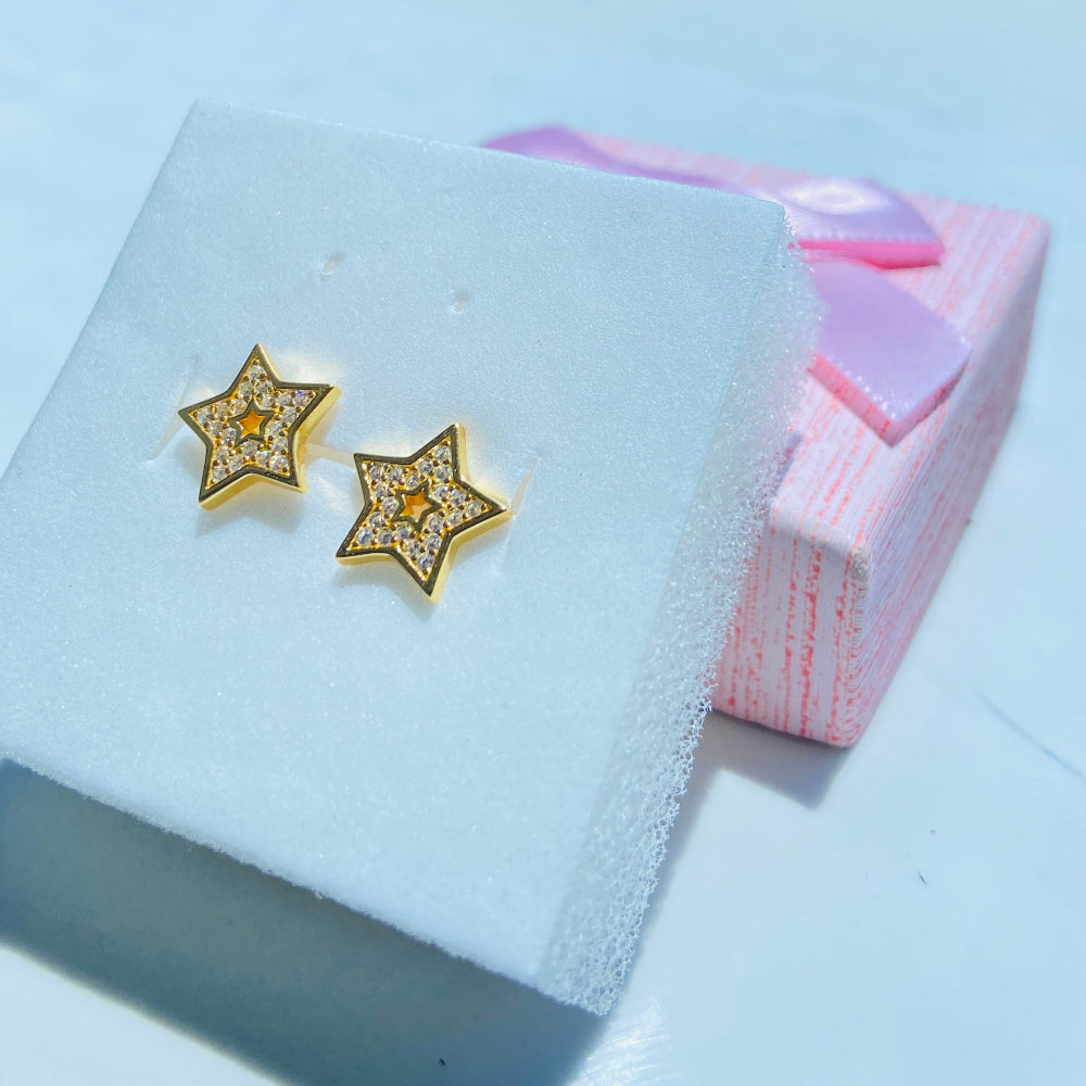 Gold star-shaped earrings on a white display card with a blurred background Gold star-shaped earrings on a white box with a scenic background gold iced star stud earring women men ladies gents kings queens 925 silver sterling silver gold plated golden shine exclusive craftsmanship Deep Shine Jewellers Jewellery jewelry trending shop now store bright beauty 