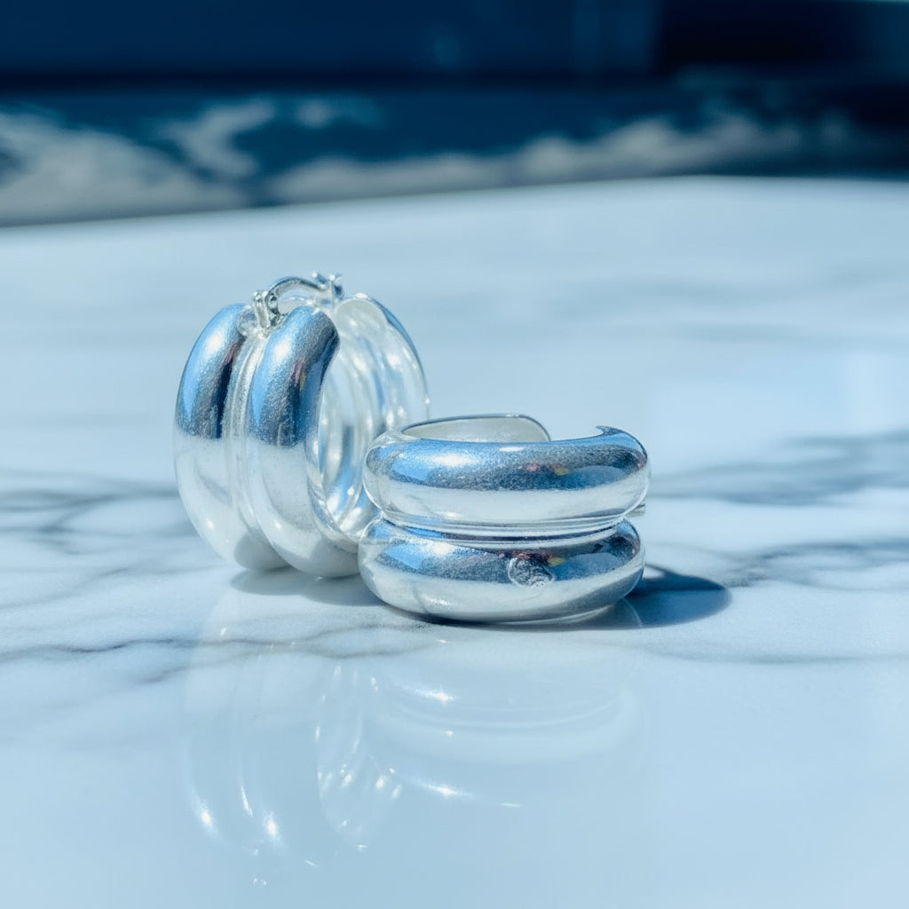 Two silver rings on a reflective surface with a blurred blue background Silver spiral earring on a white stand with a blurred background silver double hoop earrings women ladies queens 925 silver sterling silver exclusive affordable luxury jewellery jewelry Deep Shine Jewellers trending style accessories Your Time To Shine gift christmas DSJ 