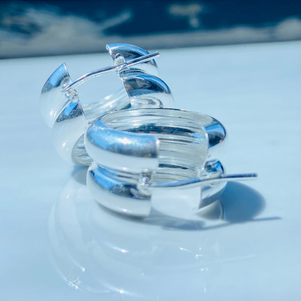 Silver ring on a light blue surface with a blurred background Silver spiral earring on a white stand with a blurred background silver double hoop earrings women ladies queens 925 silver sterling silver exclusive affordable luxury jewellery jewelry Deep Shine Jewellers trending style accessories Your Time To Shine gift christmas DSJ 