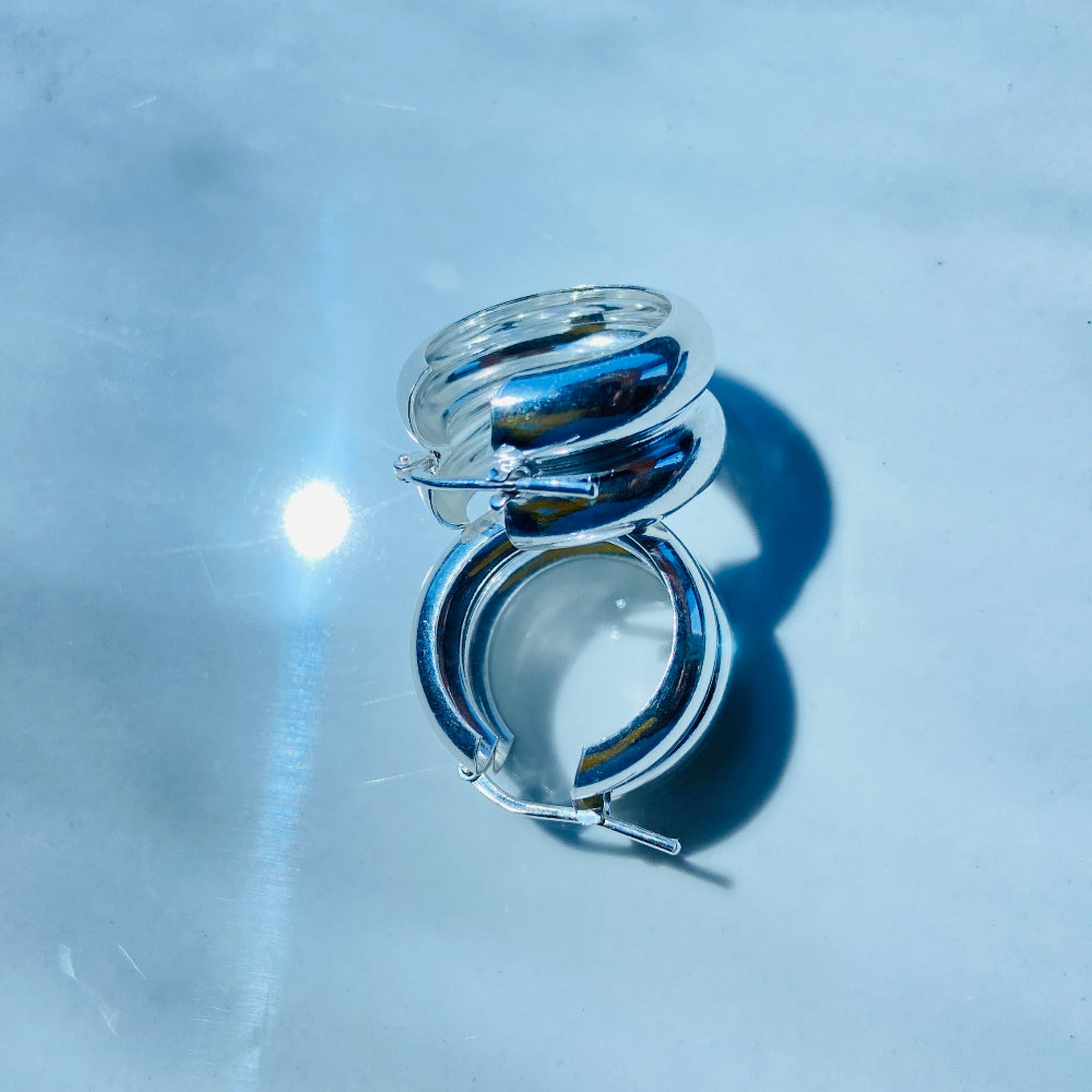 Silver ring on a light blue marble surface Silver spiral earring on a white stand with a blurred background silver double hoop earrings women ladies queens 925 silver sterling silver exclusive affordable luxury jewellery jewelry Deep Shine Jewellers trending style accessories Your Time To Shine gift christmas DSJ 
