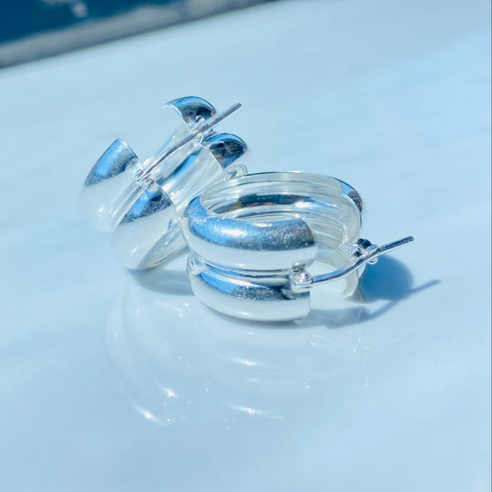 Clear plastic rings with blue accents on a light surface Silver spiral earring on a white stand with a blurred background silver double hoop earrings women ladies queens 925 silver sterling silver exclusive affordable luxury jewellery jewelry Deep Shine Jewellers trending style accessories Your Time To Shine gift christmas DSJ 