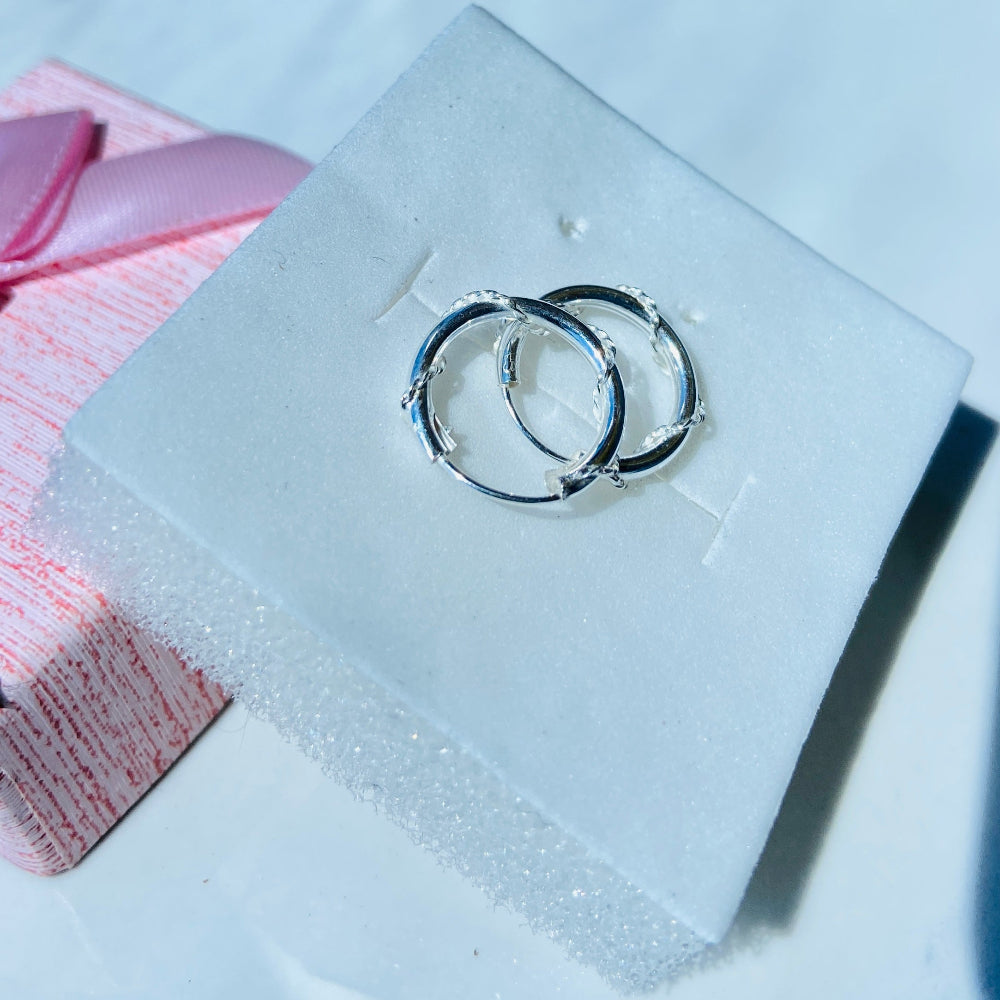 Silver hoop earrings on a clear acrylic stand with a pink fabric background Silver hoop earrings on a white box with a pink ribbon silver twisted sleeper hoop earrings for men women ladies gents queens kings 925 silver sterling silver premium quality exclusive craftsmanship Deep Shine Jewellers jewellery jewelry affordable luxury Your Time To Shine DSJ