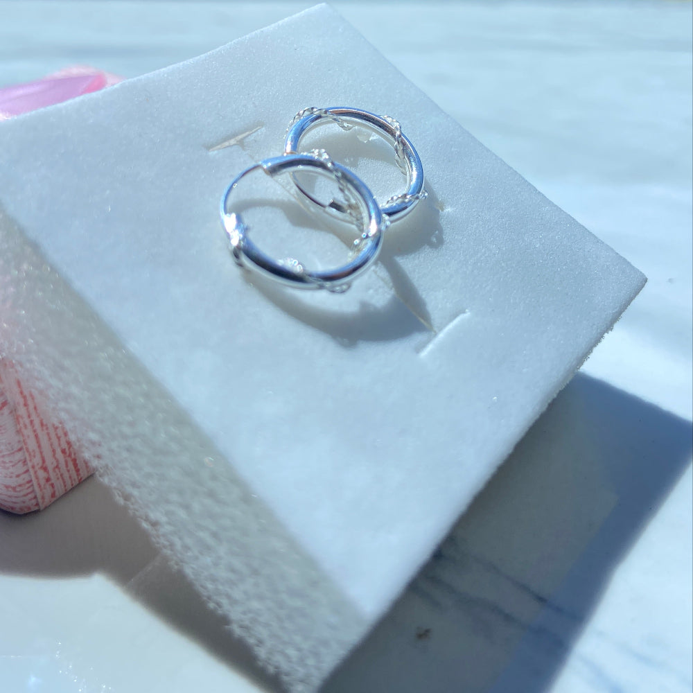 Silver hoop earrings on a white card with a blurred background Silver hoop earrings on a white box with a pink ribbon silver twisted sleeper hoop earrings for men women ladies gents queens kings 925 silver sterling silver premium quality exclusive craftsmanship Deep Shine Jewellers jewellery jewelry affordable luxury Your Time To Shine DSJ