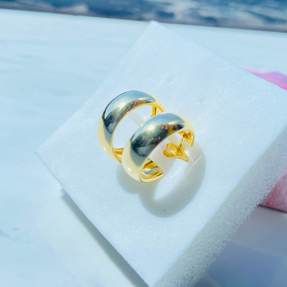 Gold ring on a white cushion with a blurred background Gold ring on a white surface with a blue background thick gold sleeper hoop earrings women ladies queens exclusive affordable luxury Deep Shine Jewellers jewellery jewelry gold plated 925 silver sterling silver Your Time To Shine DSJ craftsmanship trending shop now