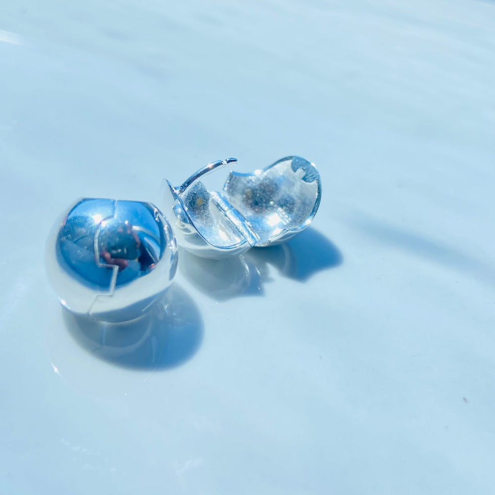 Clear heart-shaped earrings on a white surface with a blue background Silver earrings on a white surface with a blurred background silver dome earrings women ladies queens 925 silver sterling silver craftsmanship exclusive Deep Shine Jewellers jewellery jewelry Your Time To Shine elegant shop now trending
