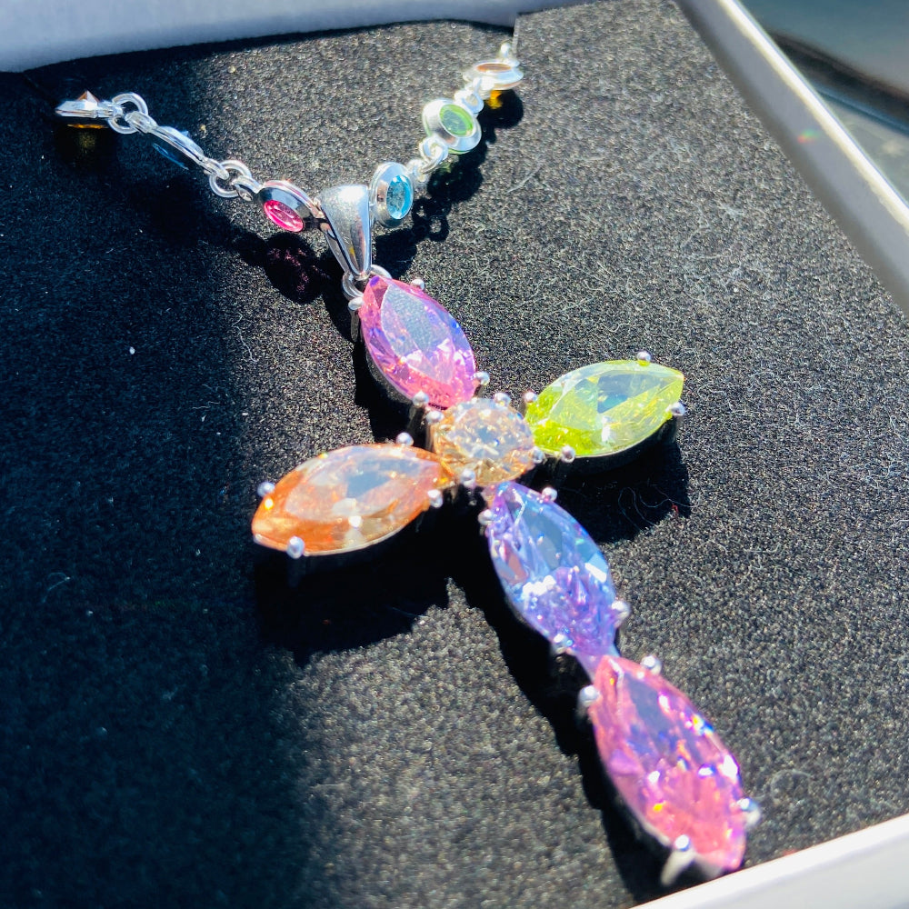 Colorful dragonfly-shaped car decal on a black surface Colorful cross-shaped pendant on a dark surface Colourful Silver Cross Jewel Chain Exclusively by Deep Shine Jewellers. colourful gemstones diamonds lab diamonds sapphire pink yellow orange purple 925 silver sterling silver exclusive craftsmanship affordable luxury premium quality jewellery jewelry trending best sellers Your Time To Shine DSJ 