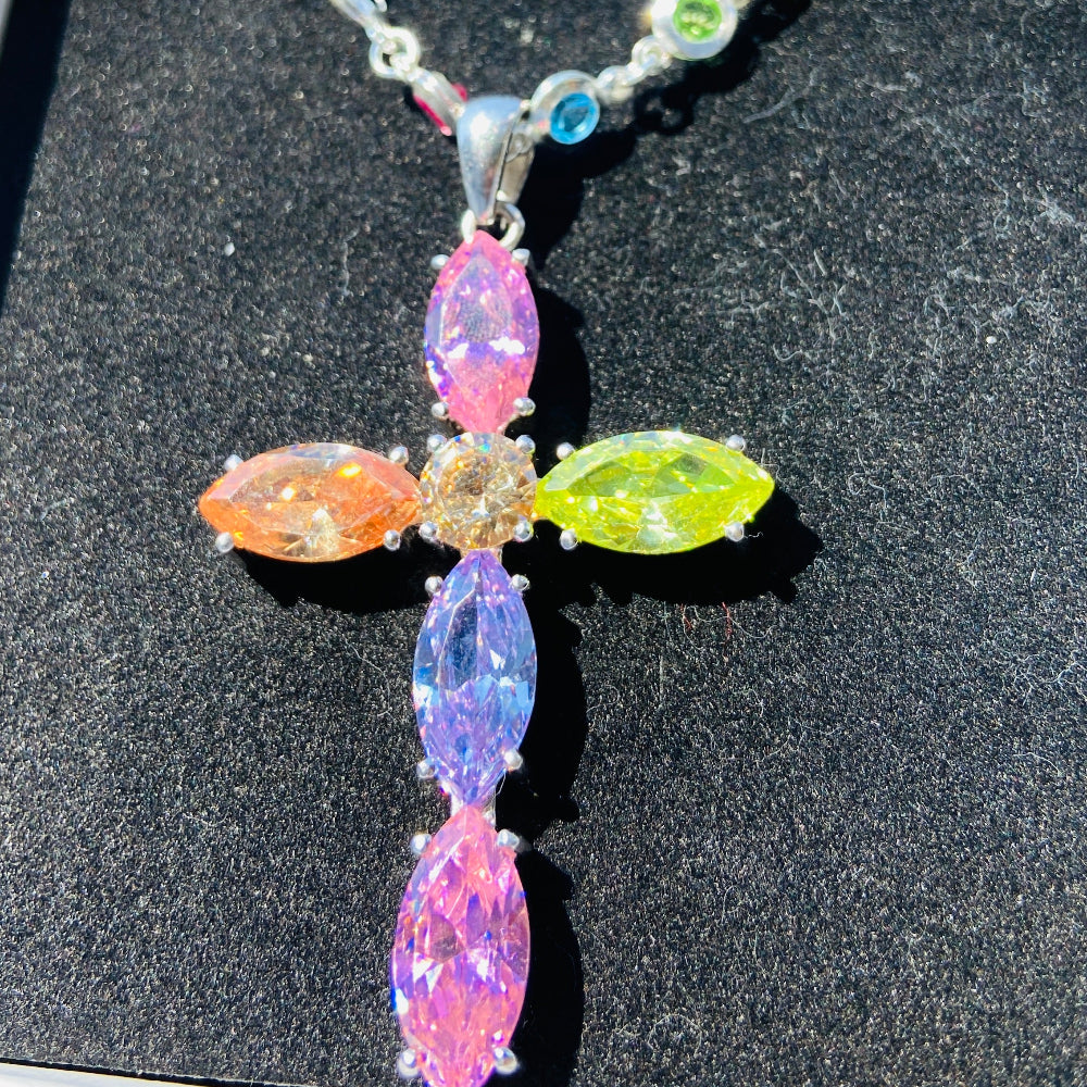 Necklace with colorful gemstones on a dark surface Colorful cross-shaped pendant on a dark surface Colourful Silver Cross Jewel Chain Exclusively by Deep Shine Jewellers. colourful gemstones diamonds lab diamonds sapphire pink yellow orange purple 925 silver sterling silver exclusive craftsmanship affordable luxury premium quality jewellery jewelry trending best sellers Your Time To Shine DSJ 