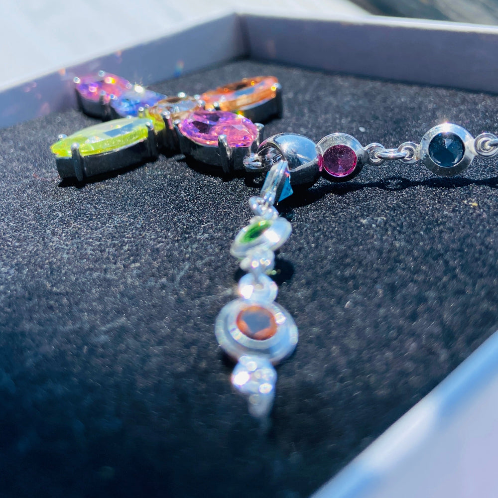 Colorful beaded bracelet on a dark surface with a blurred background Colorful cross-shaped pendant on a dark surface Colourful Silver Cross Jewel Chain Exclusively by Deep Shine Jewellers. colourful gemstones diamonds lab diamonds sapphire pink yellow orange purple 925 silver sterling silver exclusive craftsmanship affordable luxury premium quality jewellery jewelry trending best sellers Your Time To Shine DSJ 