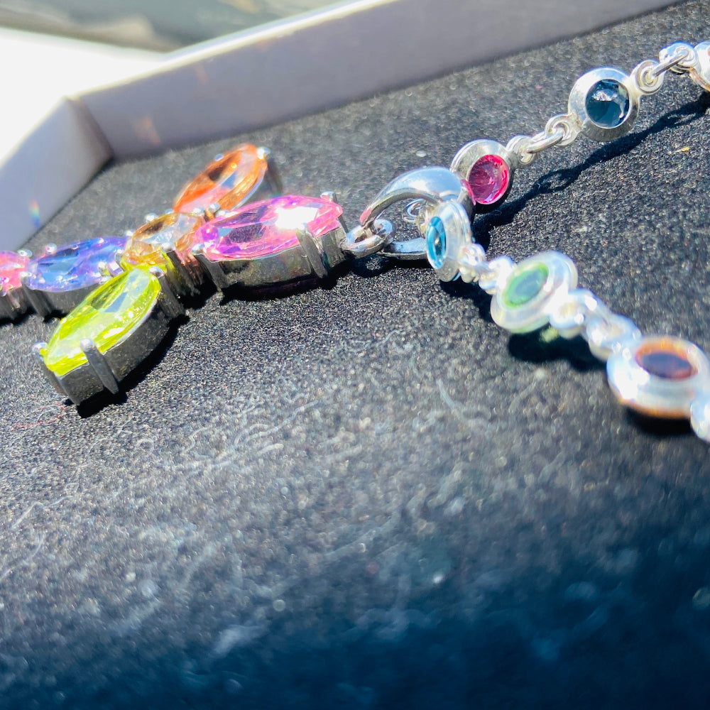 Colorful beaded bracelet with charms on a dark surface Colorful cross-shaped pendant on a dark surface Colourful Silver Cross Jewel Chain Exclusively by Deep Shine Jewellers. colourful gemstones diamonds lab diamonds sapphire pink yellow orange purple 925 silver sterling silver exclusive craftsmanship affordable luxury premium quality jewellery jewelry trending best sellers Your Time To Shine DSJ 
