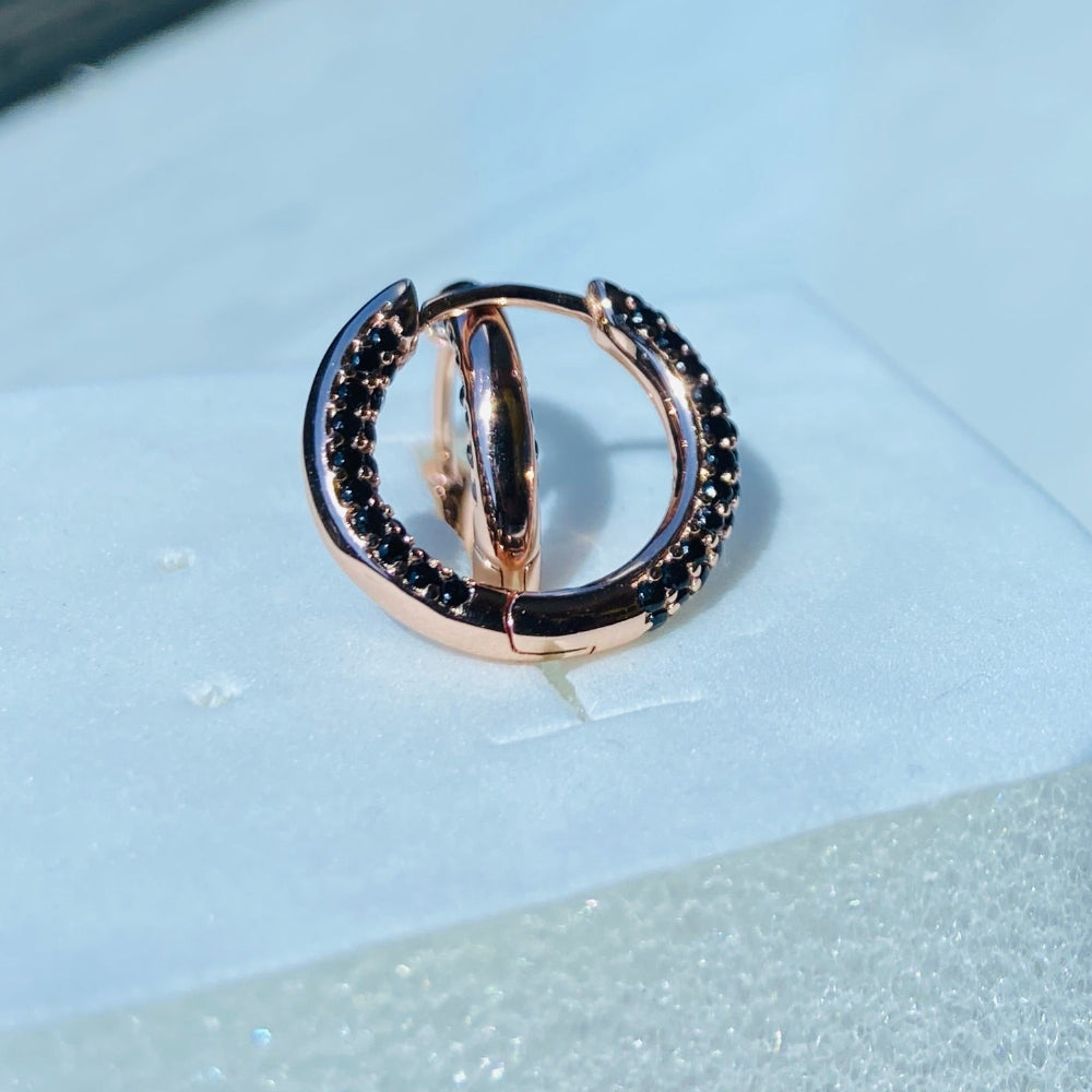 Jewelry ring with black stones on a white surfaceRose gold ring with black gemstones on a white box against a blue window background rose gold flooded sleeper hoop earrings for women ladies queens black stones black diamond cubic zirconia lab diamond 925 silver sterling silver exclusive Deep Shine Jewellers jewellery jewelry Your Time To Shine DSJ