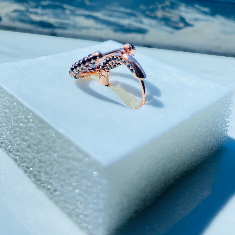 Rose gold ring on a white stand with a blue background Rose gold ring with black gemstones on a white box against a blue window background rose gold flooded sleeper hoop earrings for women ladies queens black stones black diamond cubic zirconia lab diamond 925 silver sterling silver exclusive Deep Shine Jewellers jewellery jewelry Your Time To Shine DSJ