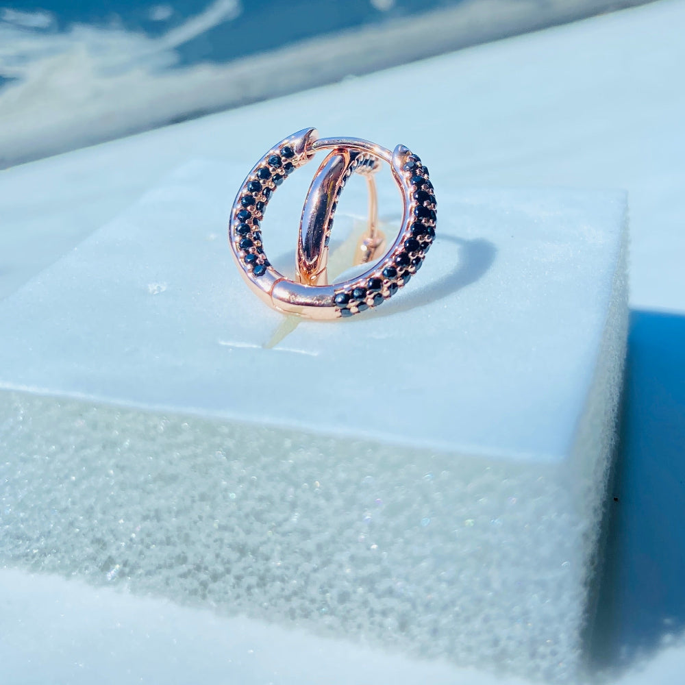 Rose gold ring with black gemstones on a white box against a blue window background rose gold flooded sleeper hoop earrings for women ladies queens black stones black diamond cubic zirconia lab diamond 925 silver sterling silver exclusive Deep Shine Jewellers jewellery jewelry Your Time To Shine DSJ