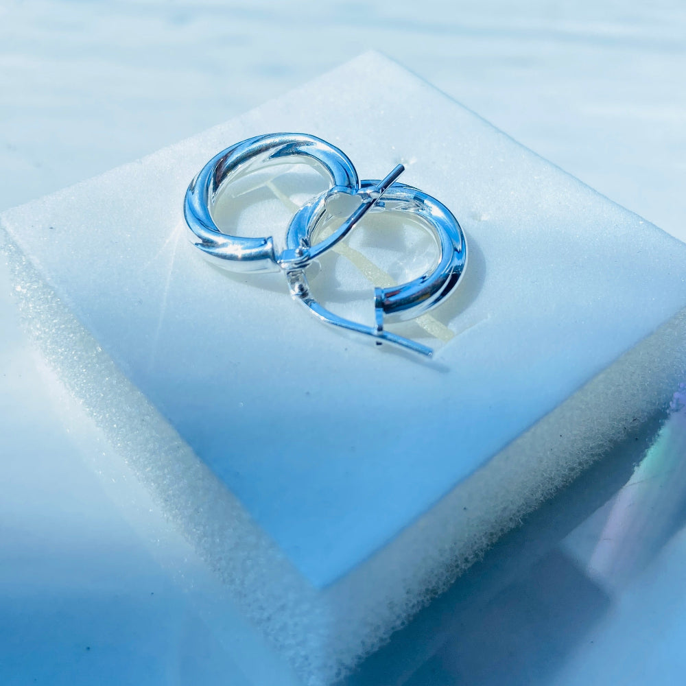 Silver ring on a white cushion with a blue background Silver hoop earrings on a white square platform with a blue background silver twist sleeper hoop earrings for women womens ladies queen 925 silver sterling silver affordable luxury jewellery jewelry trendy fashion Deep Shine Jewellers shop now DSJ 