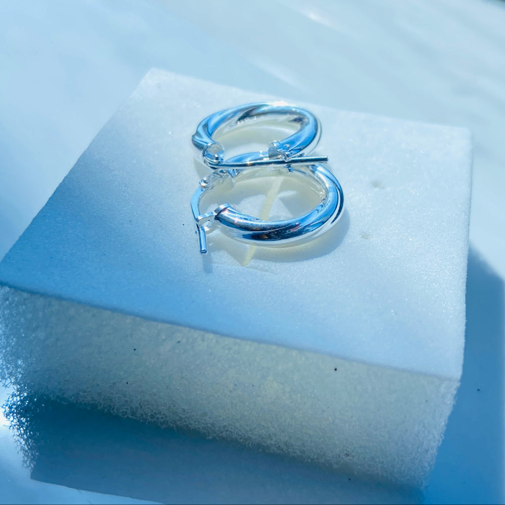 Silver ring on a white stand with a blue background Silver hoop earrings on a white square platform with a blue background silver twist sleeper hoop earrings for women womens ladies queen 925 silver sterling silver affordable luxury jewellery jewelry trendy fashion Deep Shine Jewellers shop now DSJ 